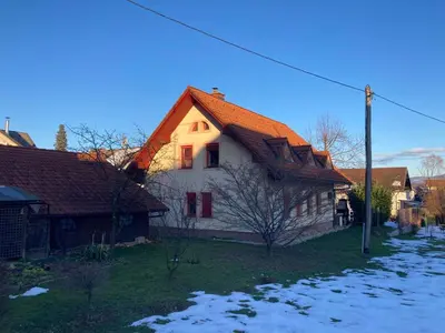 a house with an orange roof with snow on the ground at Apartma Ob Krki in Straža