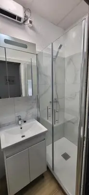 a white bathroom with a shower and a sink at Soba Kolovrat in Straža