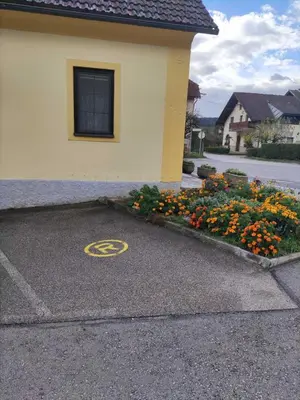 a parking lot with a peace sign and flowers at Soba Kolovrat in Straža
