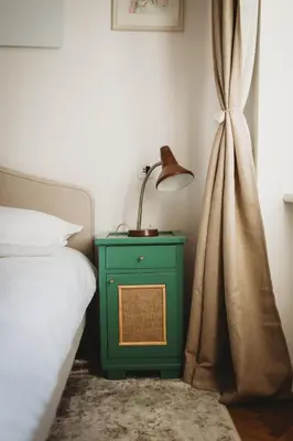 a green nightstand with a lamp on it next to a bed at The Muse' Hideaway in Ljubljana
