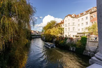 a boat on a river in a city with buildings at The Muse' Hideaway in Ljubljana