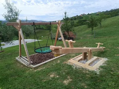 a playground with a swing in the grass at Hiška na gorci in Podčetrtek