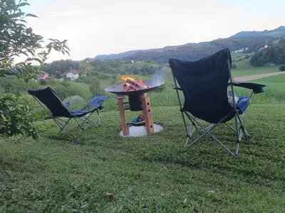 two chairs and a fire pit in the grass at Hiška na gorci in Podčetrtek