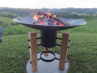 a barbecue grill with a fire in a field at Hiška na gorci in Podčetrtek