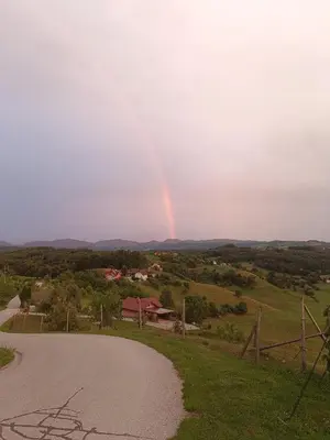 a rainbow in the sky over a road at Hiška na gorci in Podčetrtek