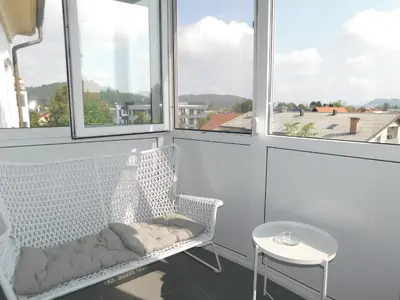 a white chair sitting in a room with windows at Elegant Apartment Poklukarjeva Street in Ljubljana