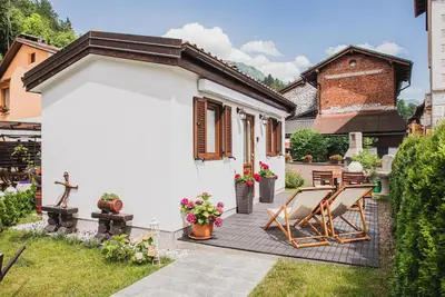 a small white house with a deck and chairs at Studio Mobile Home Gotar in Kobarid