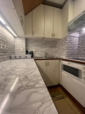 a large kitchen with marble floors and white cabinets at Little King - Feel like at home in Kranjska Gora