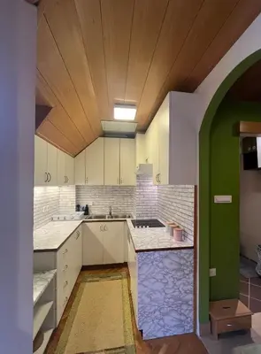 a kitchen with white cabinets and a wooden ceiling at Little King - Feel like at home in Kranjska Gora