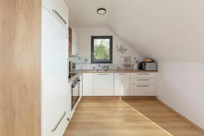 an attic kitchen with white cabinets and a wooden floor at Apartments Nikolaj in Preddvor
