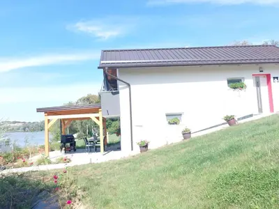 a white house with a porch and a lawn at Apartma Ob jezeru in Gradišče v Slovenskih Goricah