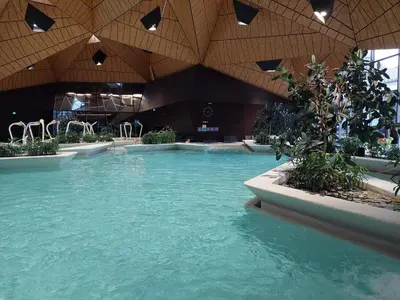a large swimming pool with blue water in a building at F96 TERME OLIMIA, Aqualuna KAMP NATURA PODČETRTEK card included all year in Podčetrtek