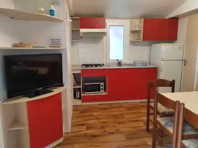 a small kitchen with red cabinets and a television at F96 TERME OLIMIA, Aqualuna KAMP NATURA PODČETRTEK card included all year in Podčetrtek