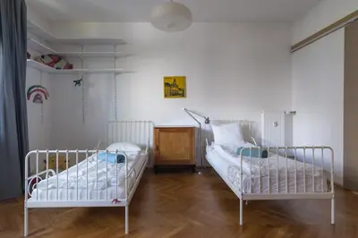 two beds in a room with white walls and wooden floors at Family apartment in the city centre - FREE parking garage in Ljubljana