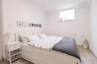 a white bedroom with a bed and a window at Apartment below Eden in Bled