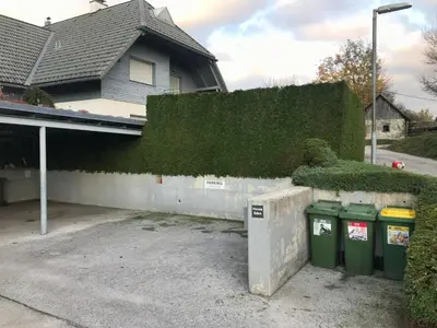 a house with two trash cans next to a wall at Apartment below Eden in Bled