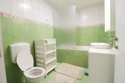 a green and white bathroom with a toilet and a sink at Apartment below Eden in Bled