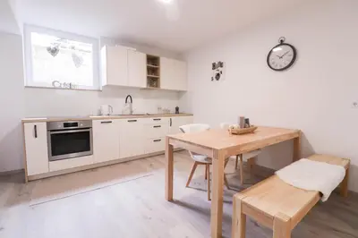 a kitchen with white cabinets and a wooden table at Apartment below Eden in Bled