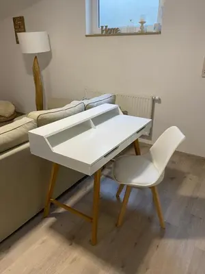 a white table and a chair in a living room at Apartment below Eden in Bled