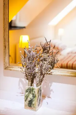 a vase with flowers on a table in front of a mirror at House Trta in Ljubljana
