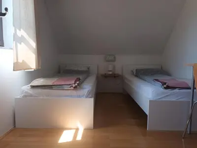 two twin beds in a room with a window at House Trta in Ljubljana
