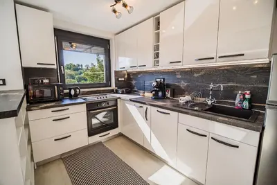 a kitchen with white cabinets and a sink and a window at Holiday Home Aleks in Lendava