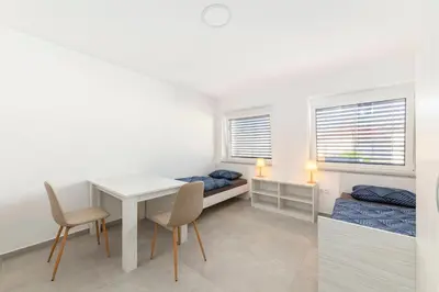 a room with a desk and a bed and a table and chairs at RM Roma Studio in Celje