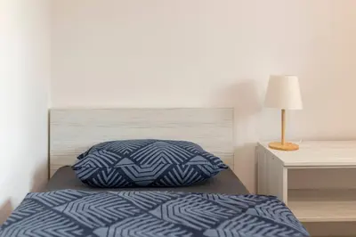 a bed with a blue and white pillow on it at RM Roma Studio in Celje