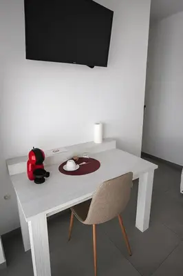 a white desk with a chair and a television at RM Roma Studio in Celje