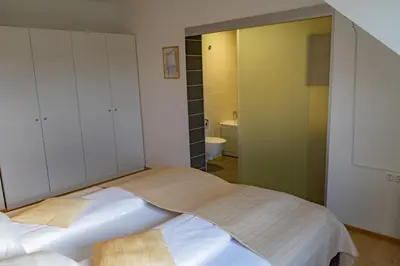 a bedroom with a large bed and a bathroom at Apartmajska hiša Breza in Ribnica na Pohorju