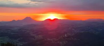a sunset over a mountain range with the sun setting at apartment AURORA in Rogaška Slatina