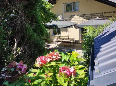 a garden with flowers and umbrellas in front of a building at Sax Pub Hostel Ljubljana in Ljubljana