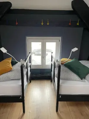 two twin beds in a room with a window at Sax Pub Hostel Ljubljana in Ljubljana