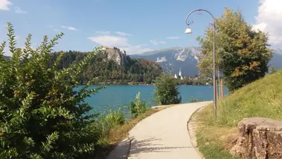 a path next to a lake with a mountain at Apartments Poklukar in Bled