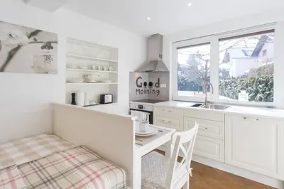 a kitchen with white cabinets and a table and a window at Apartments Poklukar in Bled