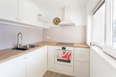 a white kitchen with white cabinets and a sink at Apartments Poklukar in Bled