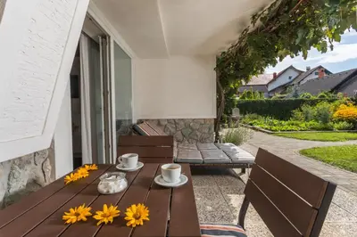 a wooden table with yellow flowers on a patio at Apartments Poklukar in Bled