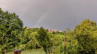 a rainbow in the sky over a river with trees at Vila Jasna in Radovljica