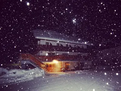 a building in the snow at night at Guest house Pr Ambružarju & Apartments in Cerklje na Gorenjskem