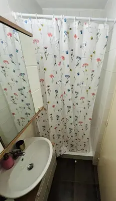 a bathroom with a sink and a shower curtain with flowers at Paula’s cosy place in the center of Ljubljana in Ljubljana