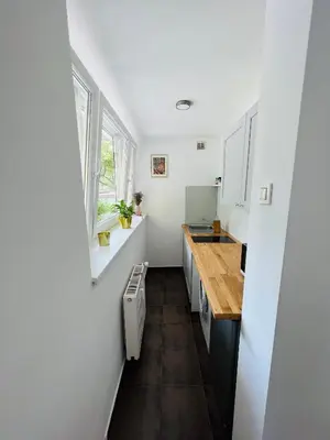 a small kitchen with white cabinets and a wooden floor at Paula’s cosy place in the center of Ljubljana in Ljubljana