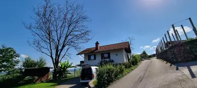 a house with a car parked next to a road at Marinčeva zidanica in Črnomelj