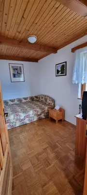 a living room with a bed and a wooden ceiling at Marinčeva zidanica in Črnomelj