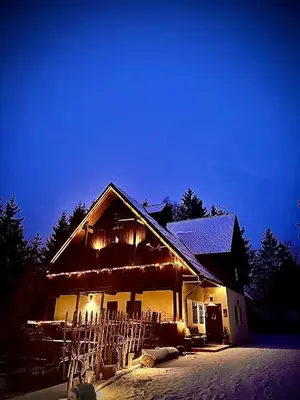 a house with a fence in the snow at night at Pomona Relaxing Nature Guest House in Rogaška Slatina
