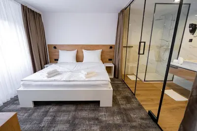 a bedroom with a white bed and a glass shower at City Hotel Krško in Krško