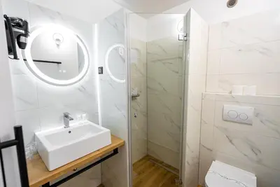 a white bathroom with a sink and a shower at City Hotel Krško in Krško