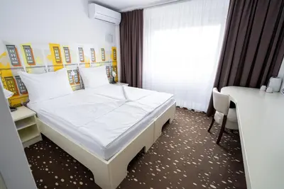 a bedroom with a bed and a desk and a window at City Hotel Krško in Krško