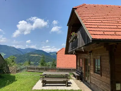 a wooden picnic table next to a building with a bench at A View to a Hill in Sveti Florijan pri Šoštanju