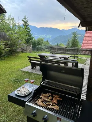 a grill with a plate of food and two glasses of wine at A View to a Hill in Sveti Florijan pri Šoštanju
