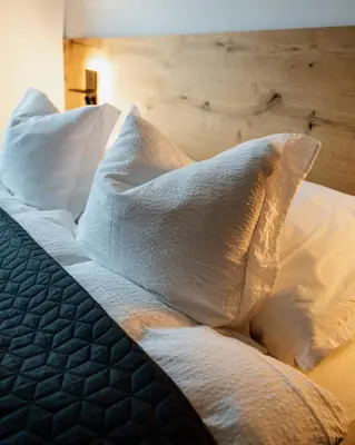 a bed with white sheets and pillows on it at Posestvo Gjerkeš in Rogašovci